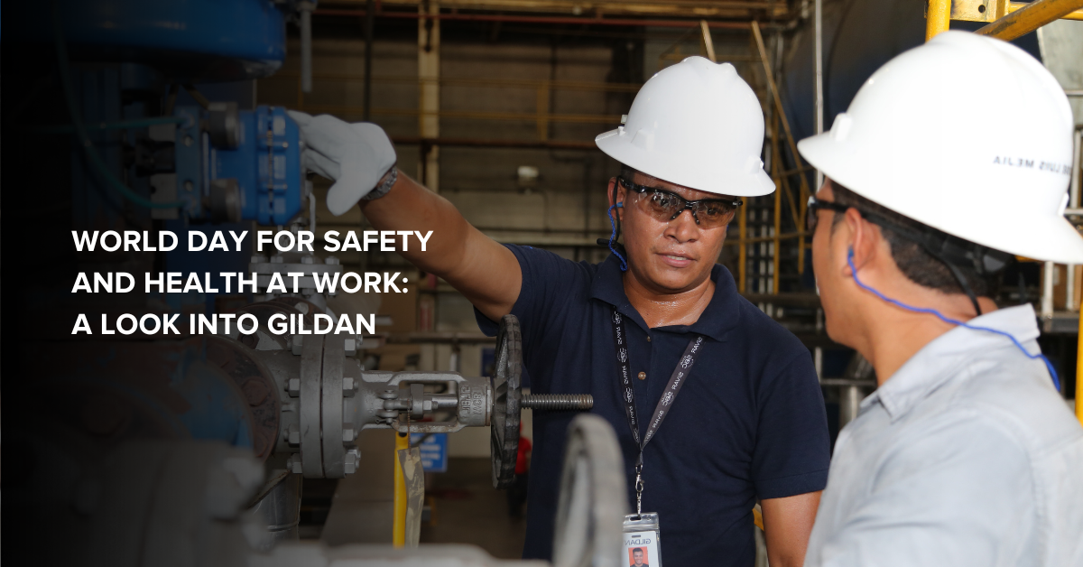 Two Gildan employees wearing safety equipment, interacting on the factory floor