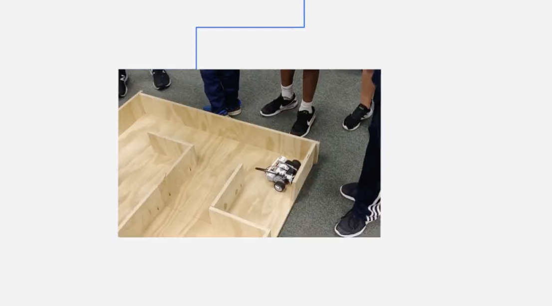 students standing around a wooden maze for a robotic vehicle