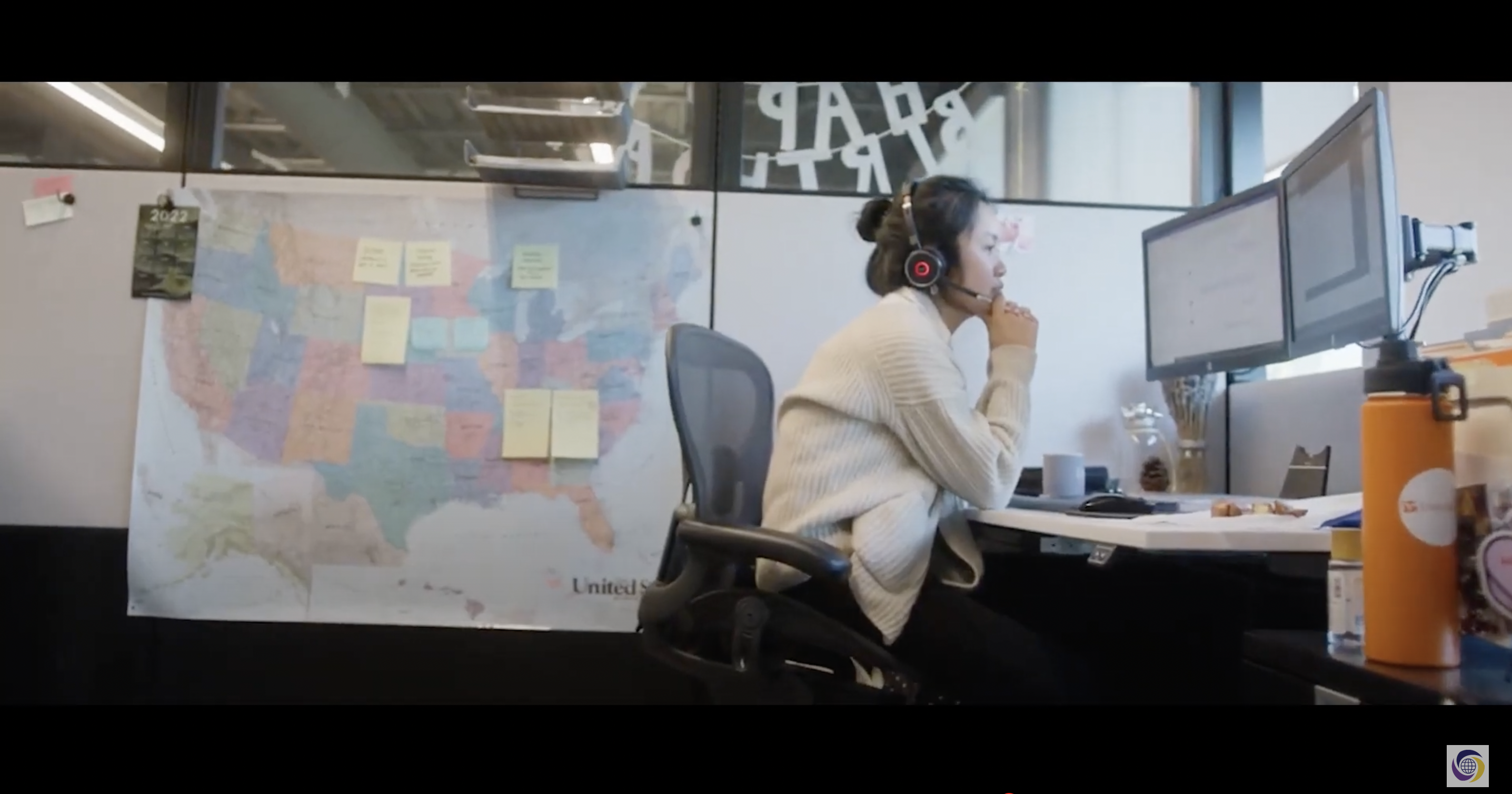 worker in a headset sitting at a desk in front of a map of the US