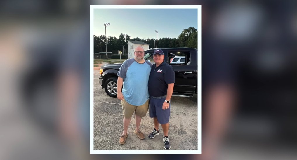 two men standing together in front of truck 