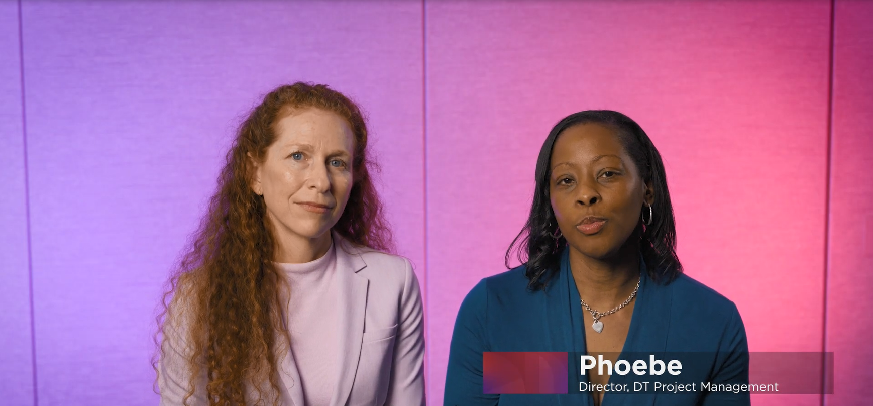 Two people sitting next to each other, a colorful backdrop behind them