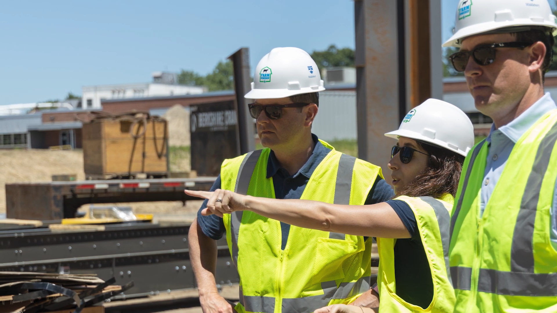 Three people wearing hi-vis vests and hard hards while on site
