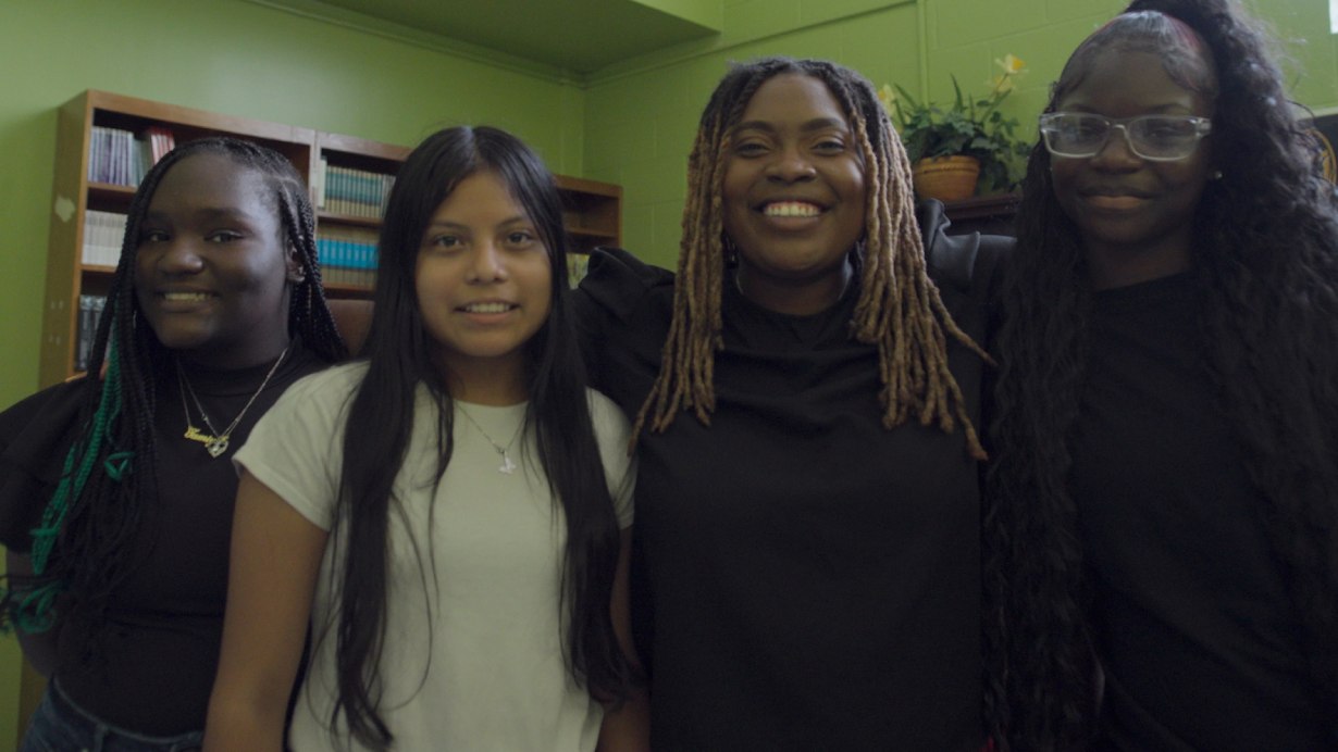 Four people with arms around each other, smiling.