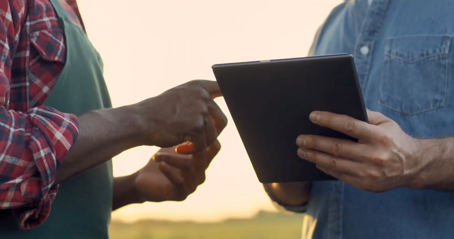 Two people close together outside. One using a tablet device.