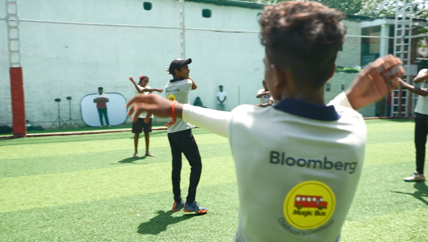 People stretching in a grass courtyard, wearing matching shirts "Bloomberg Magic Bus" 