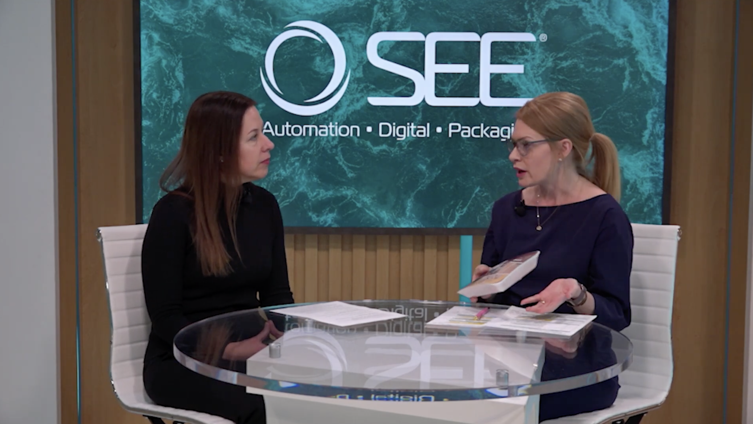 2 people talking in front of SEE logo