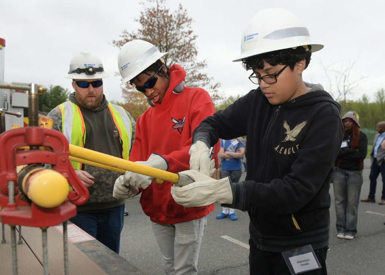 students in hard hats working on equipment outside