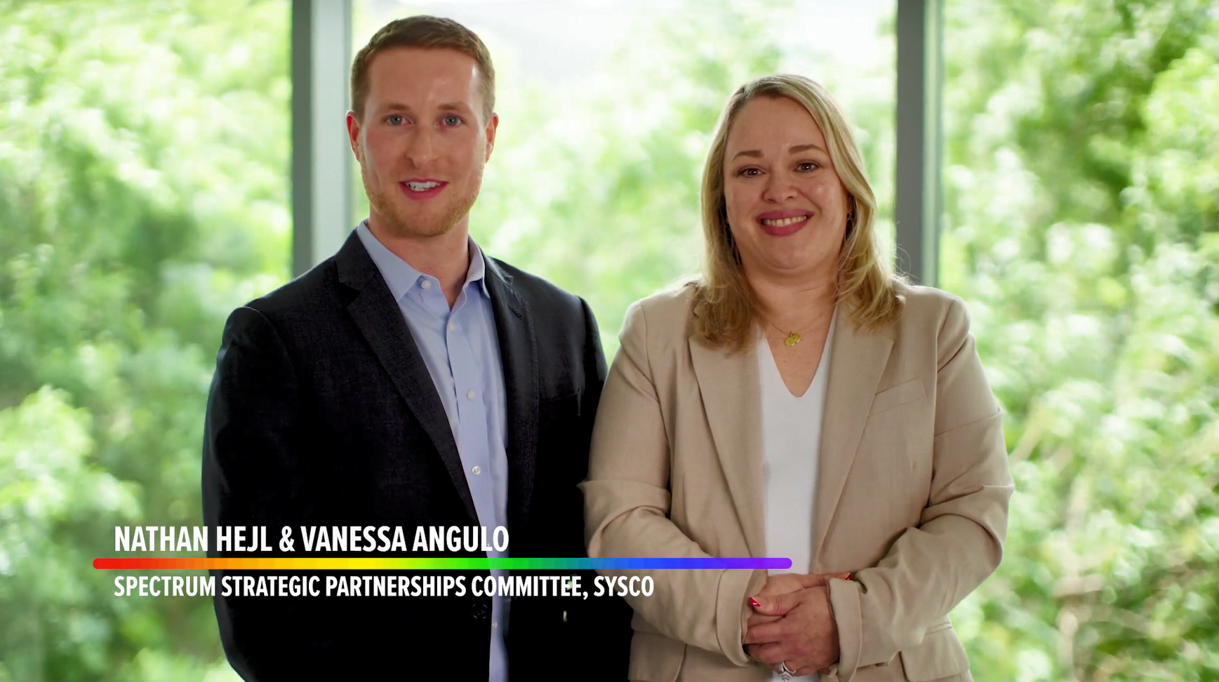 Two employees with titles posed in a corridor.