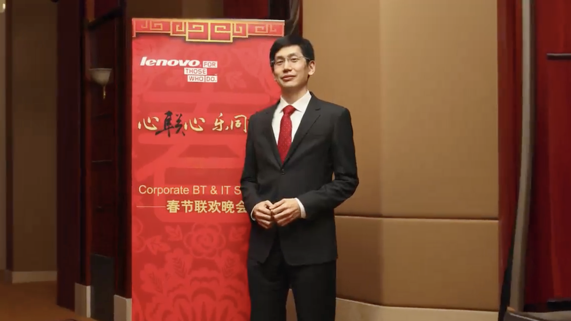 Authur Hu wearing a suit while stood in front of a Lenovo event banner 