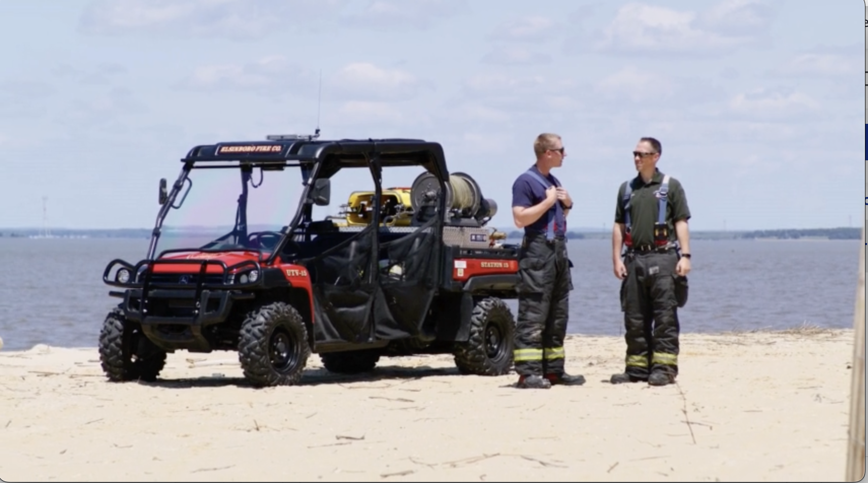 The Fire Department's utility terrain vehicle parked on a beach with two men standing nearby