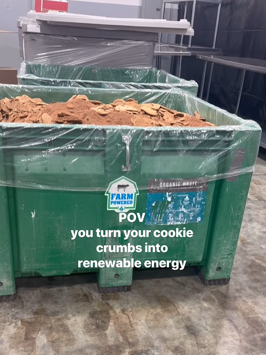 A large green bin filled with waste cookies and crumbs. "POV you turn your cookie crumbs into renewable energy"