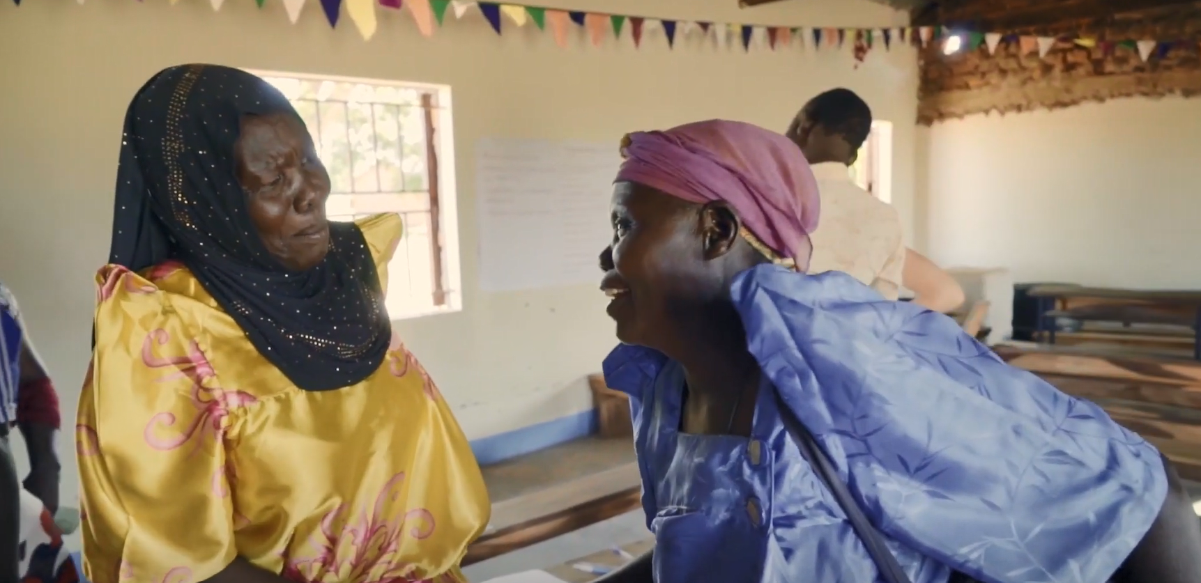 Two people smiling, talking to each other.