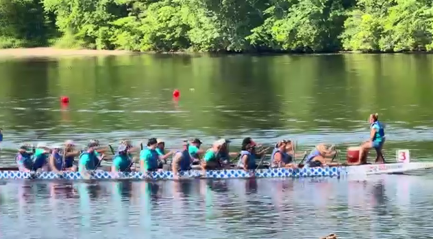 A team rowing in a dragon boat on a body of water.