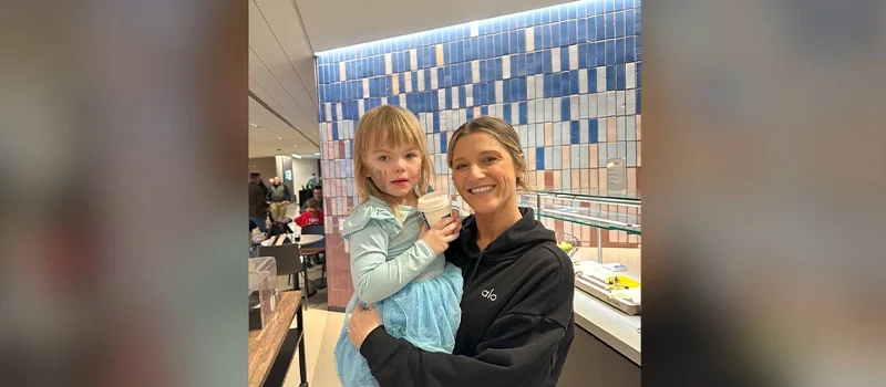 Britney Ruby Miller holding a child in a cafeteria setting.