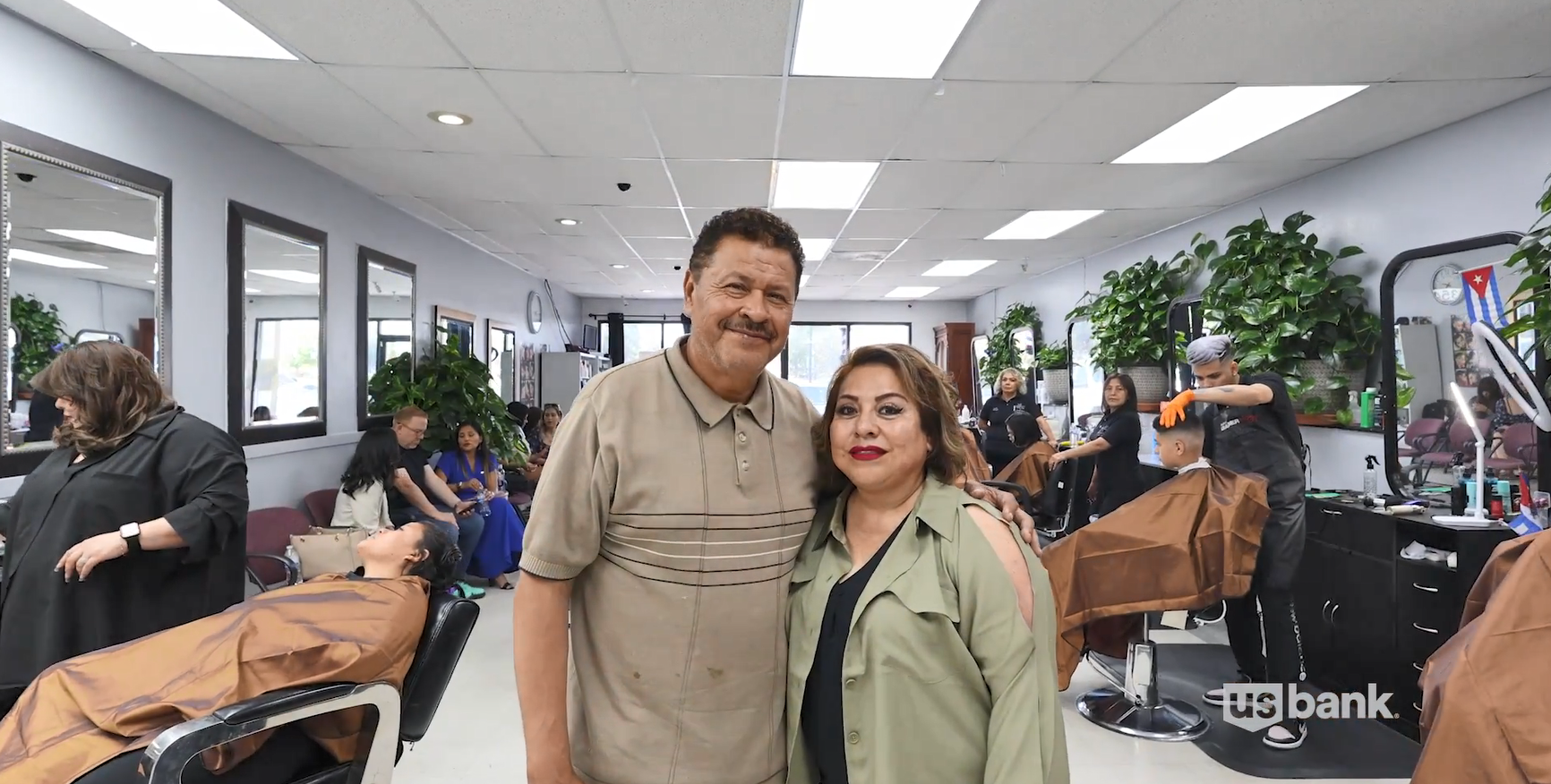 Luz and Juan Andrade standing in a busy barber shop.