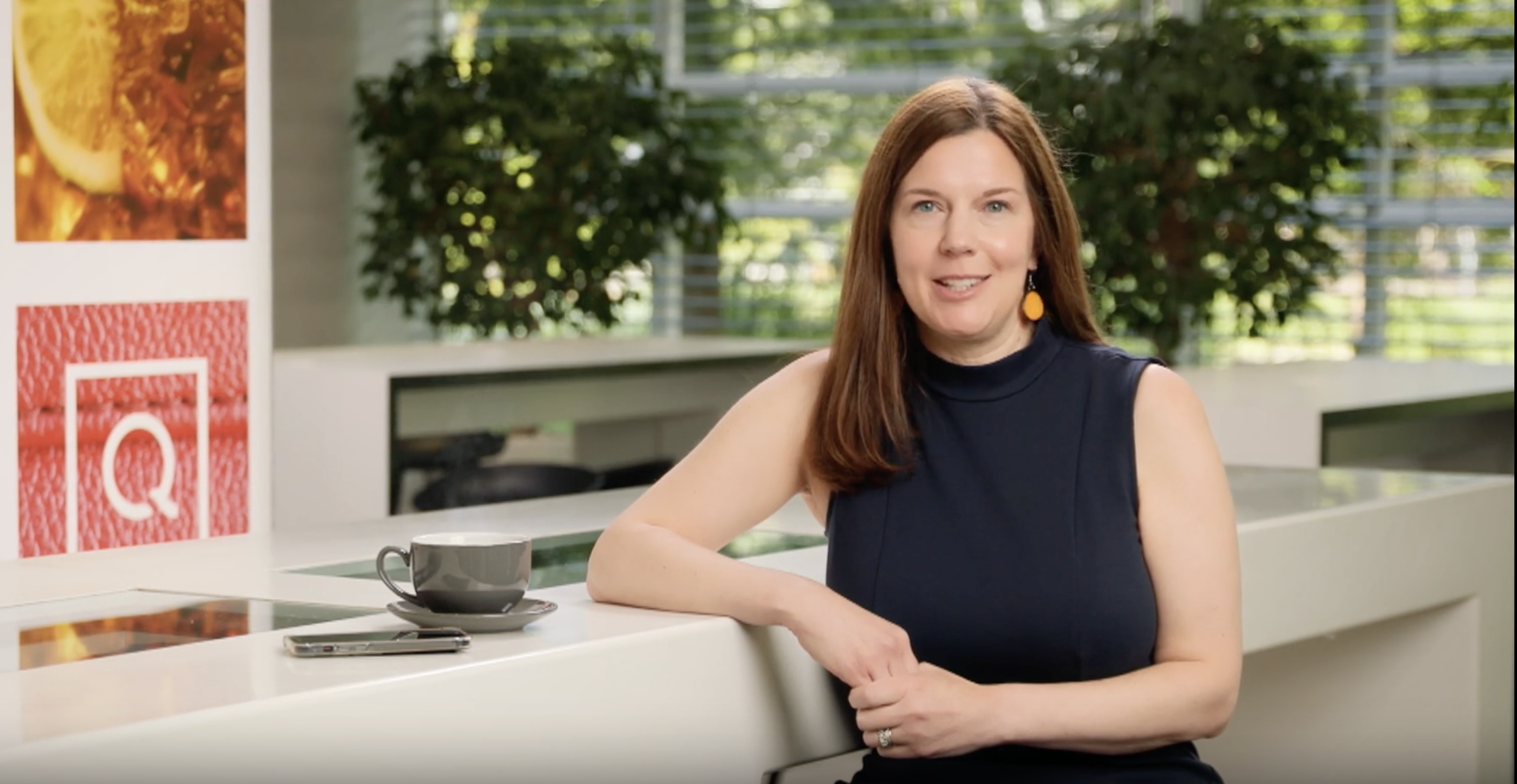 Woman sitting at a desk with her phone and a teacup nearby