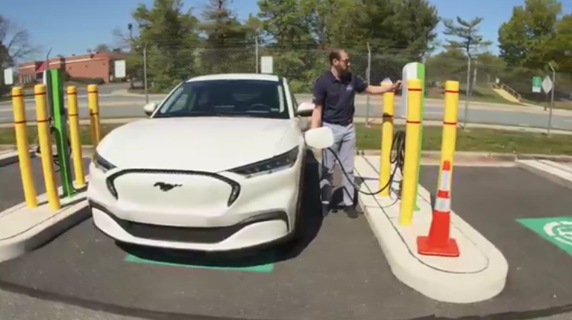 A person next to a vehicle and charging station
