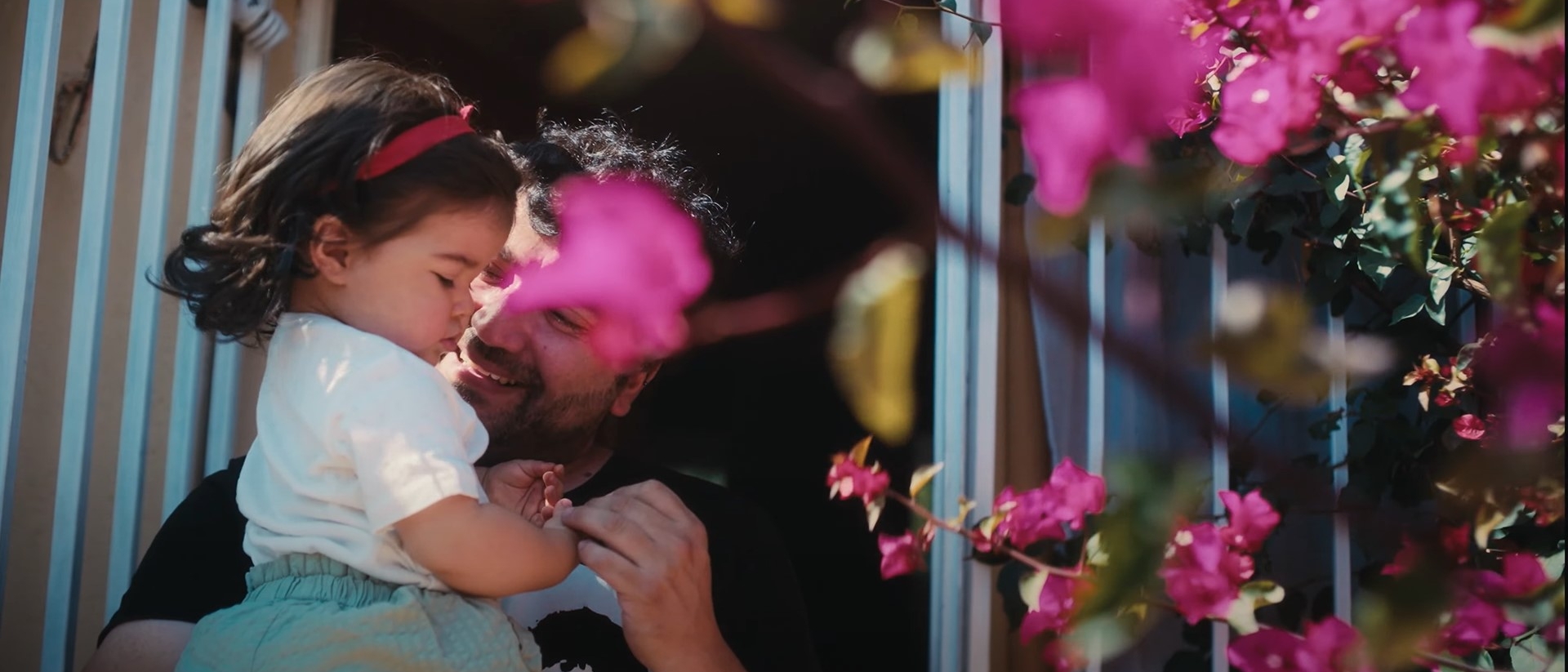 Smiling man holding baby with flowers blossoming around them
