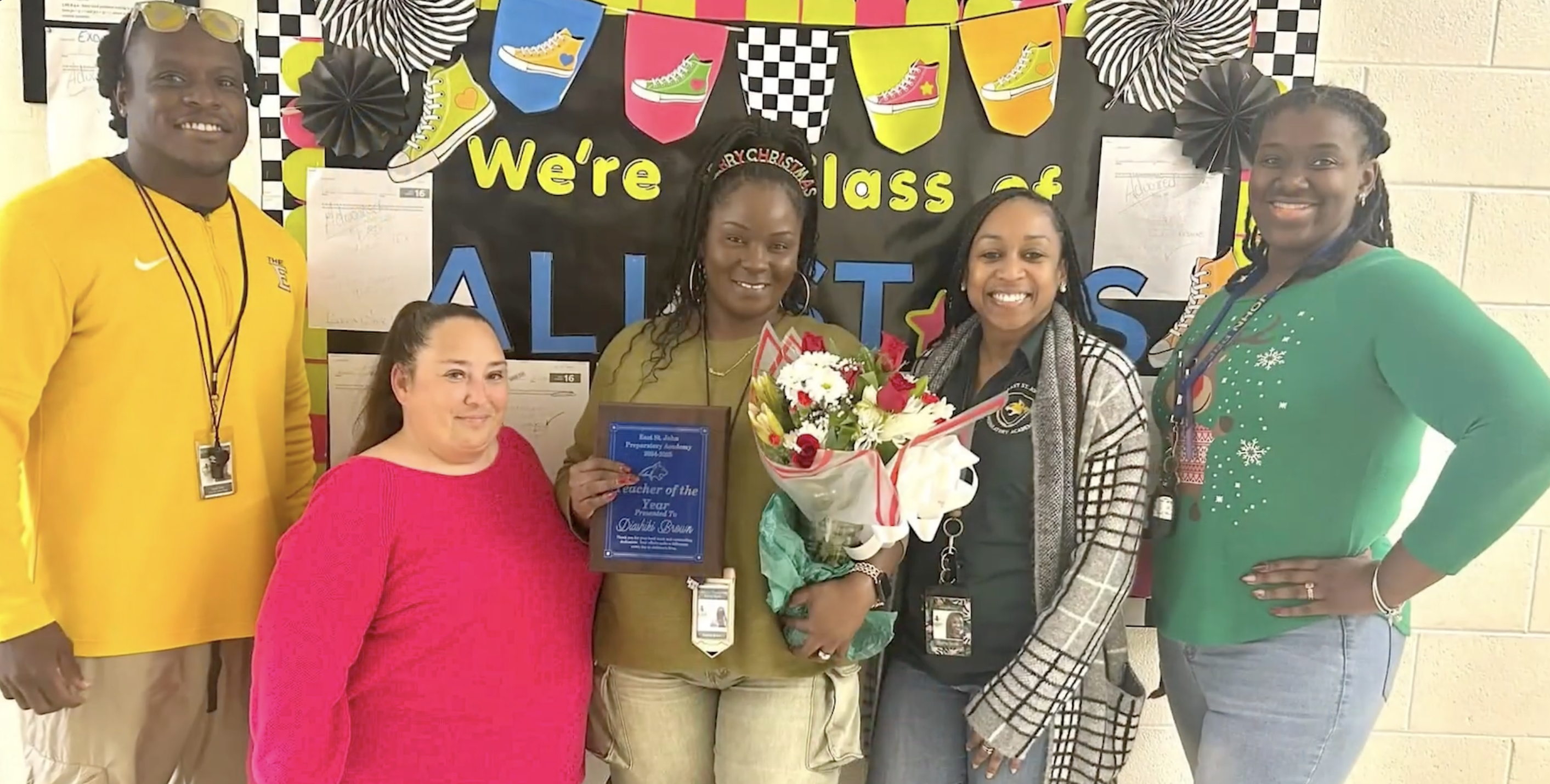 Diashiki Snyder-Brown holding a bunch of flowers in front of a blackboard