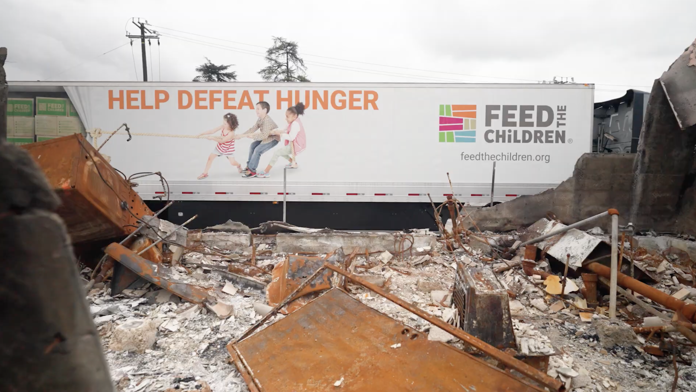 Feed the Children truck behind burnt structure