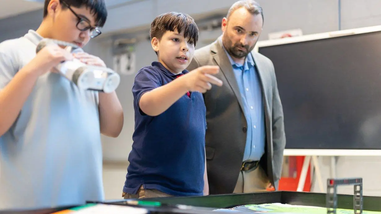 Greg Pardo looks over two students