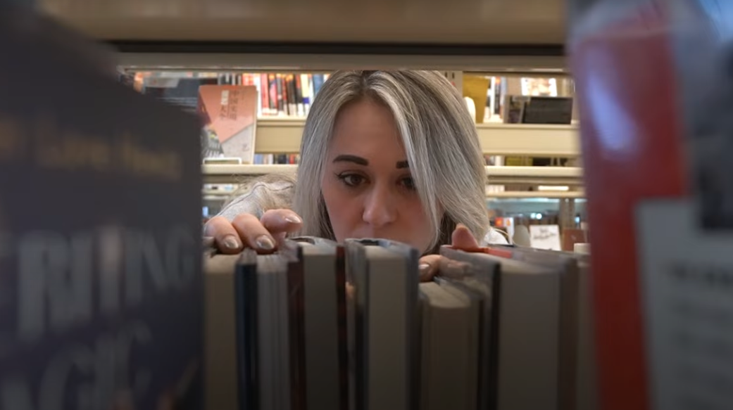 Someone looking through a bookshelf