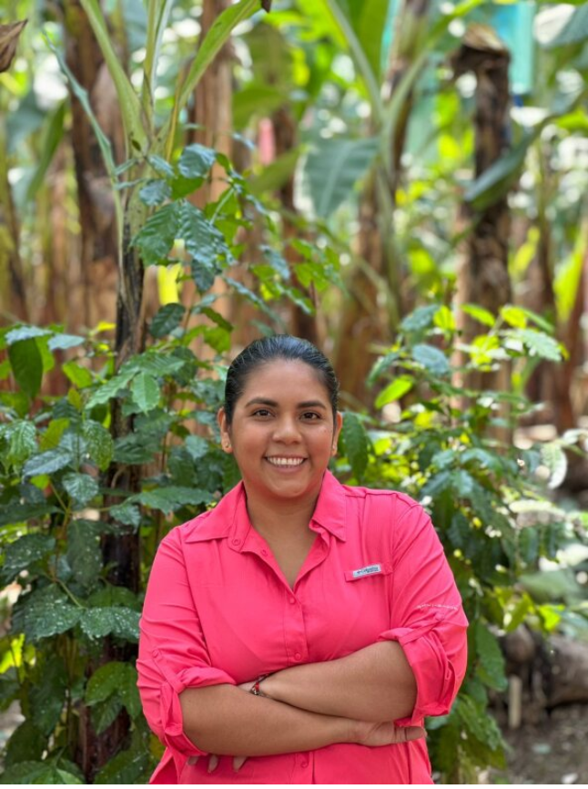 Ana, a banana farmer in Ecuador, stands near banana plants and explains how they grow in generations. 