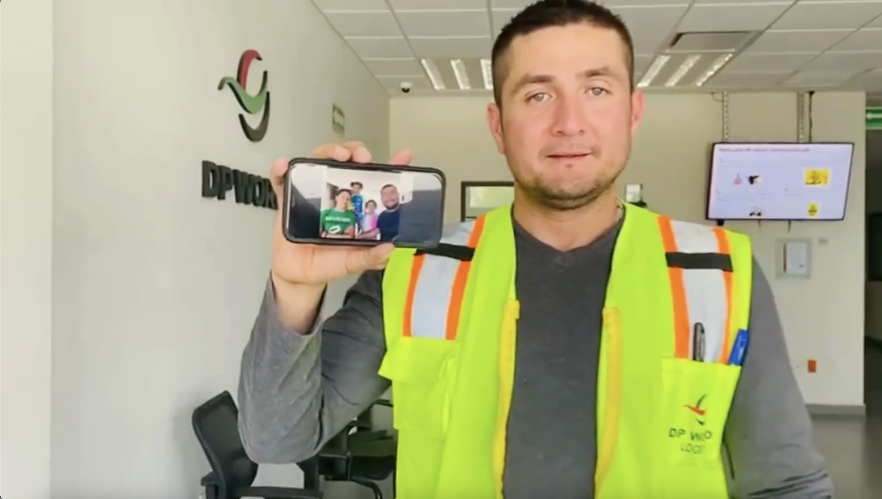 Man holding a phone with picture of his family on it