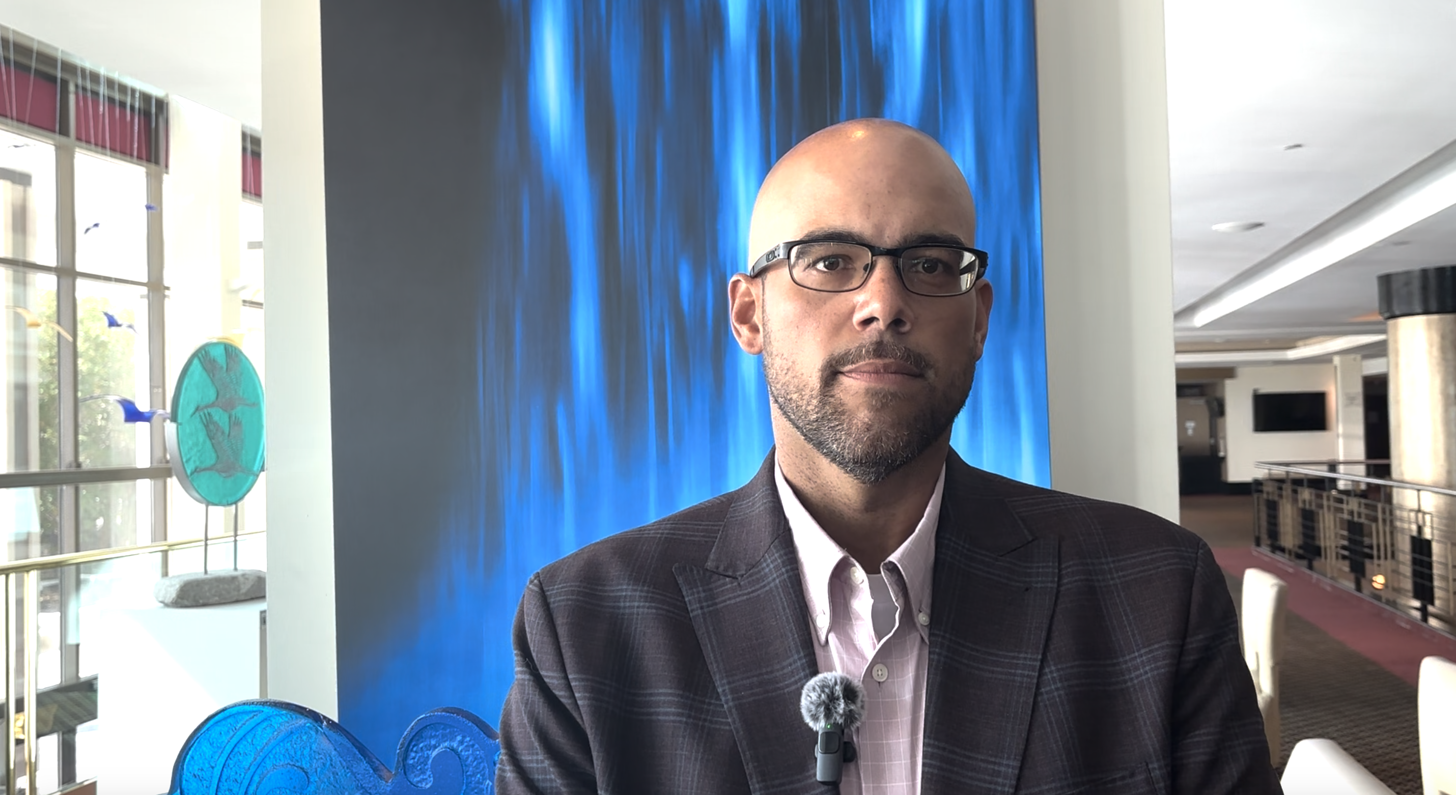 Man wearing glasses in front of backdrop