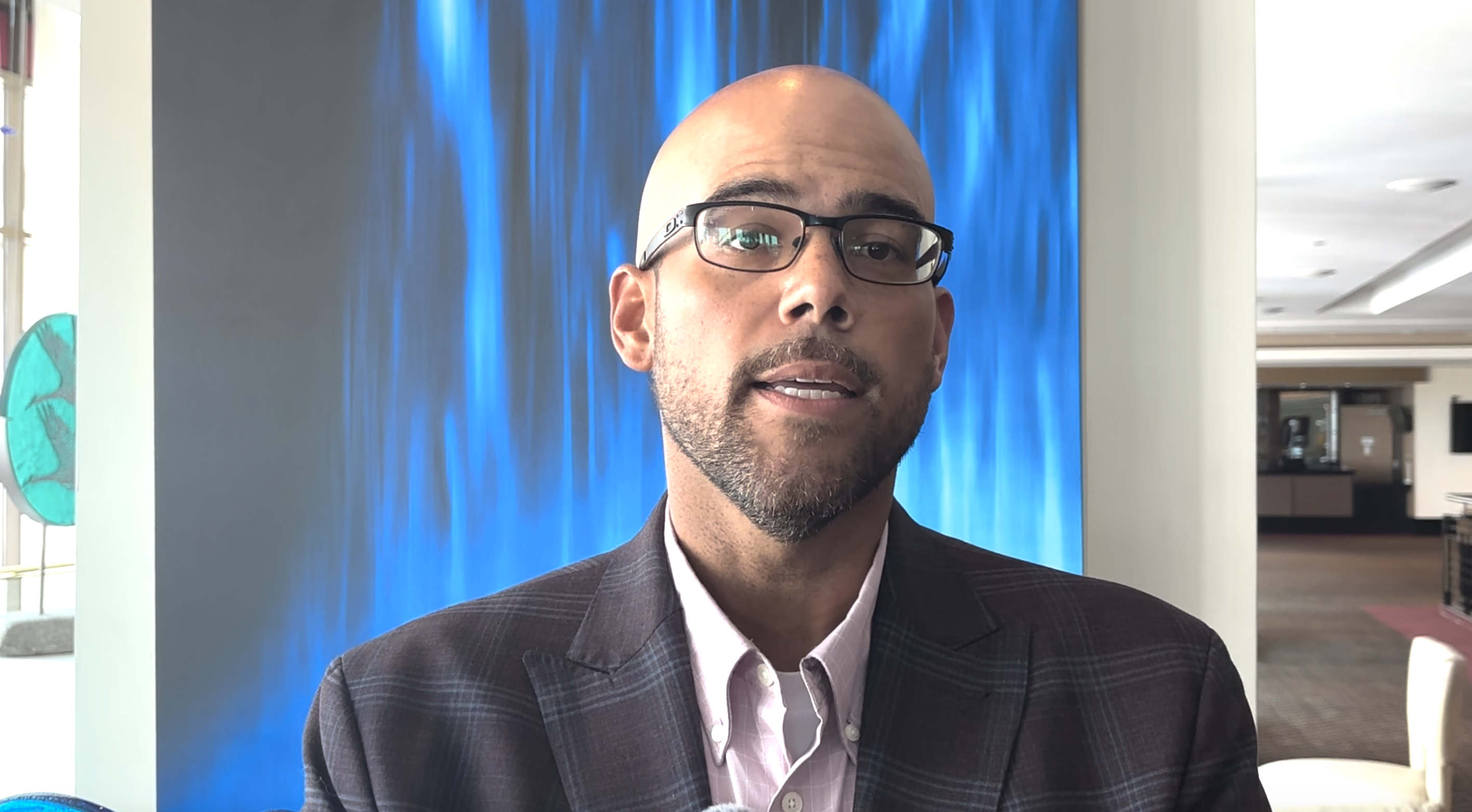 Man wearing glasses in front of backdrop
