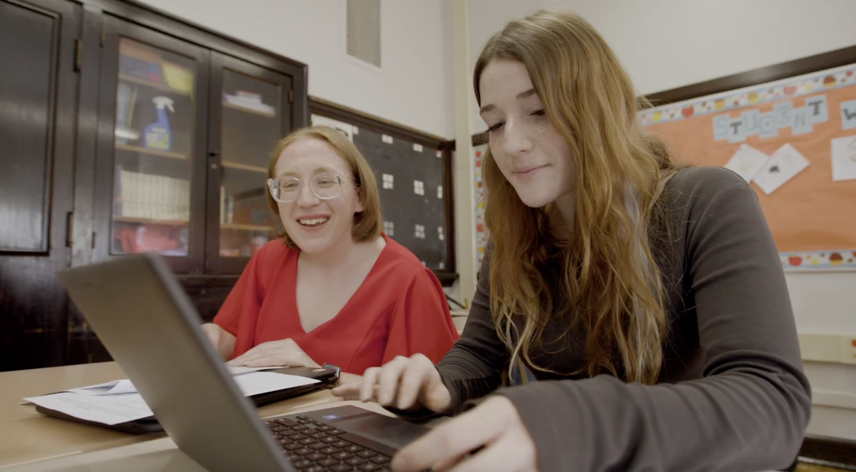 Educator and student working on a laptop