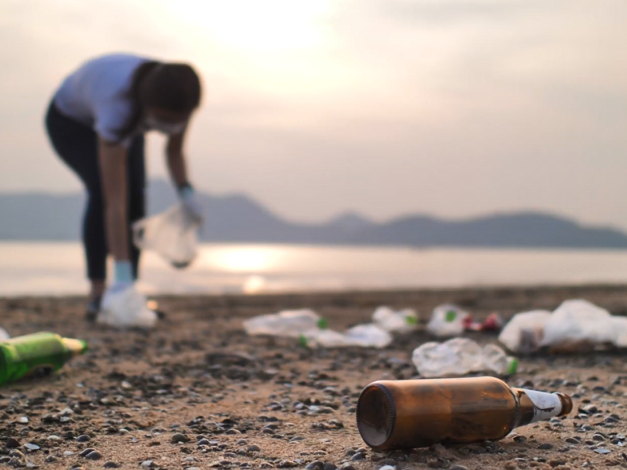 Two people picking up trash on a beach.