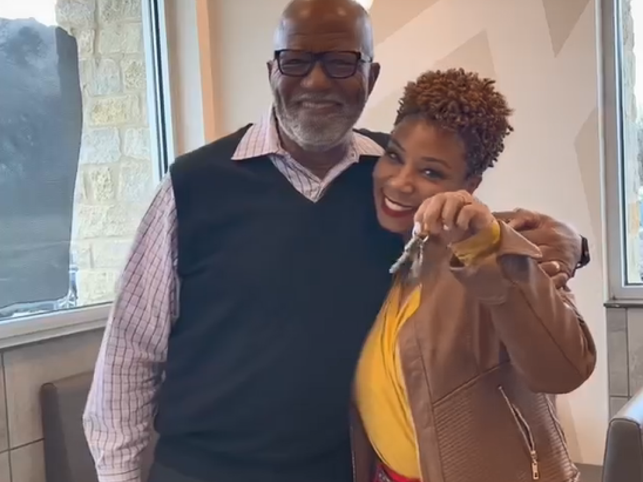 Aaron Harris and Joy Silmon with arms around each other, Joy holds a set of keys.