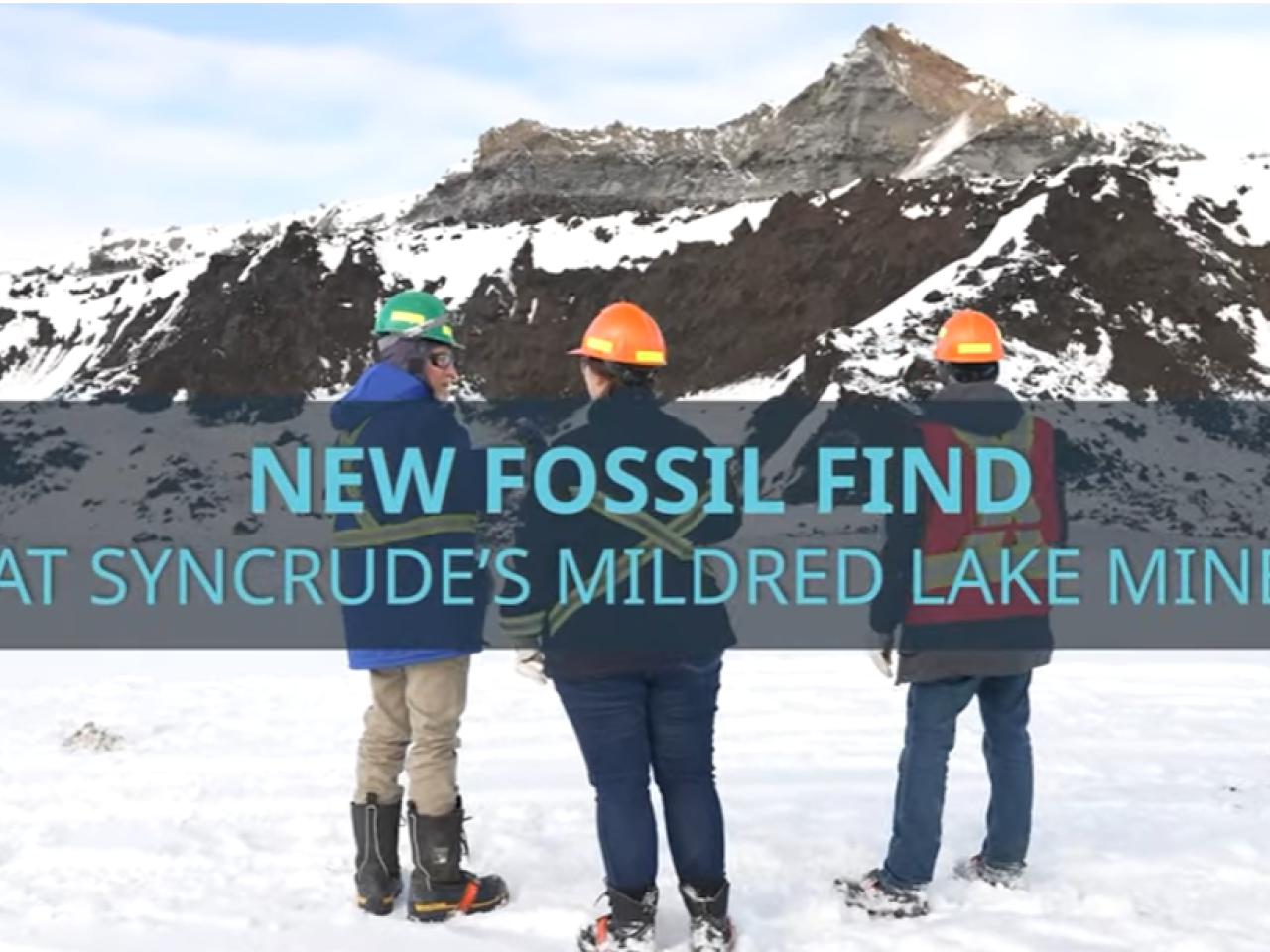 People standing in front of mountain with text "New Fossil Find at Syncrude's Mildred Lake Mine"
