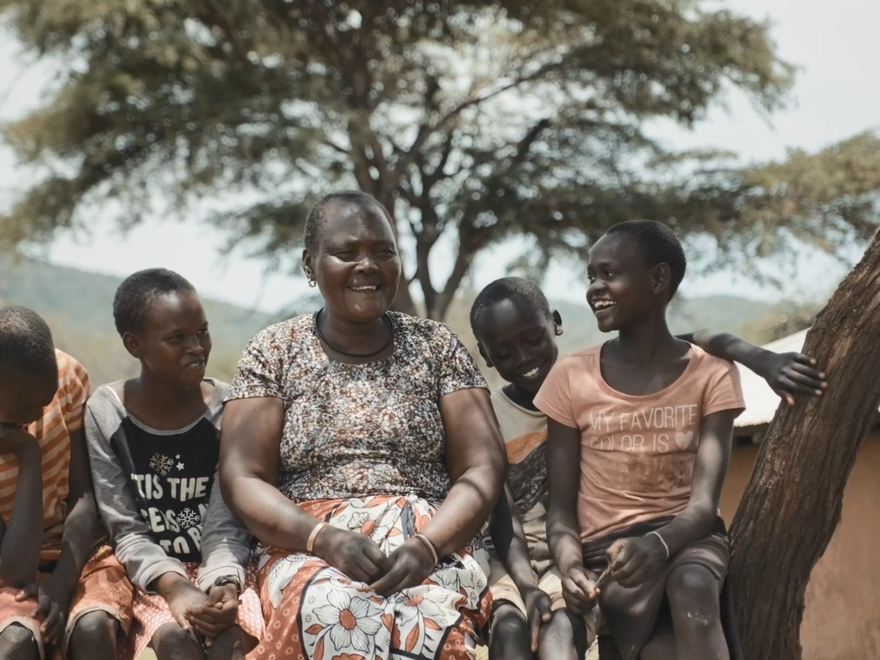 Lucy Tomee and four children sitting on a bench outside.