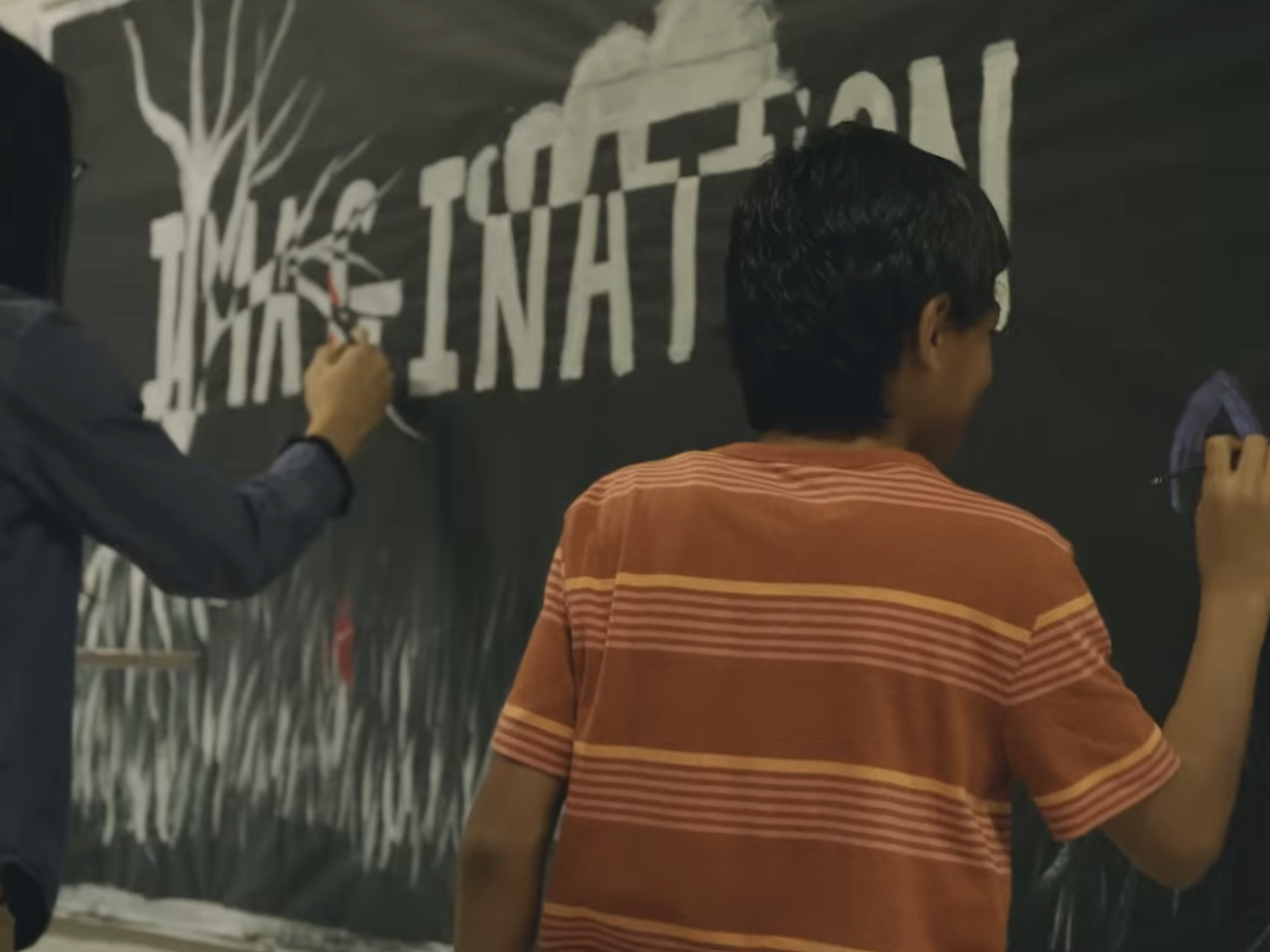 A child writing on a black board 