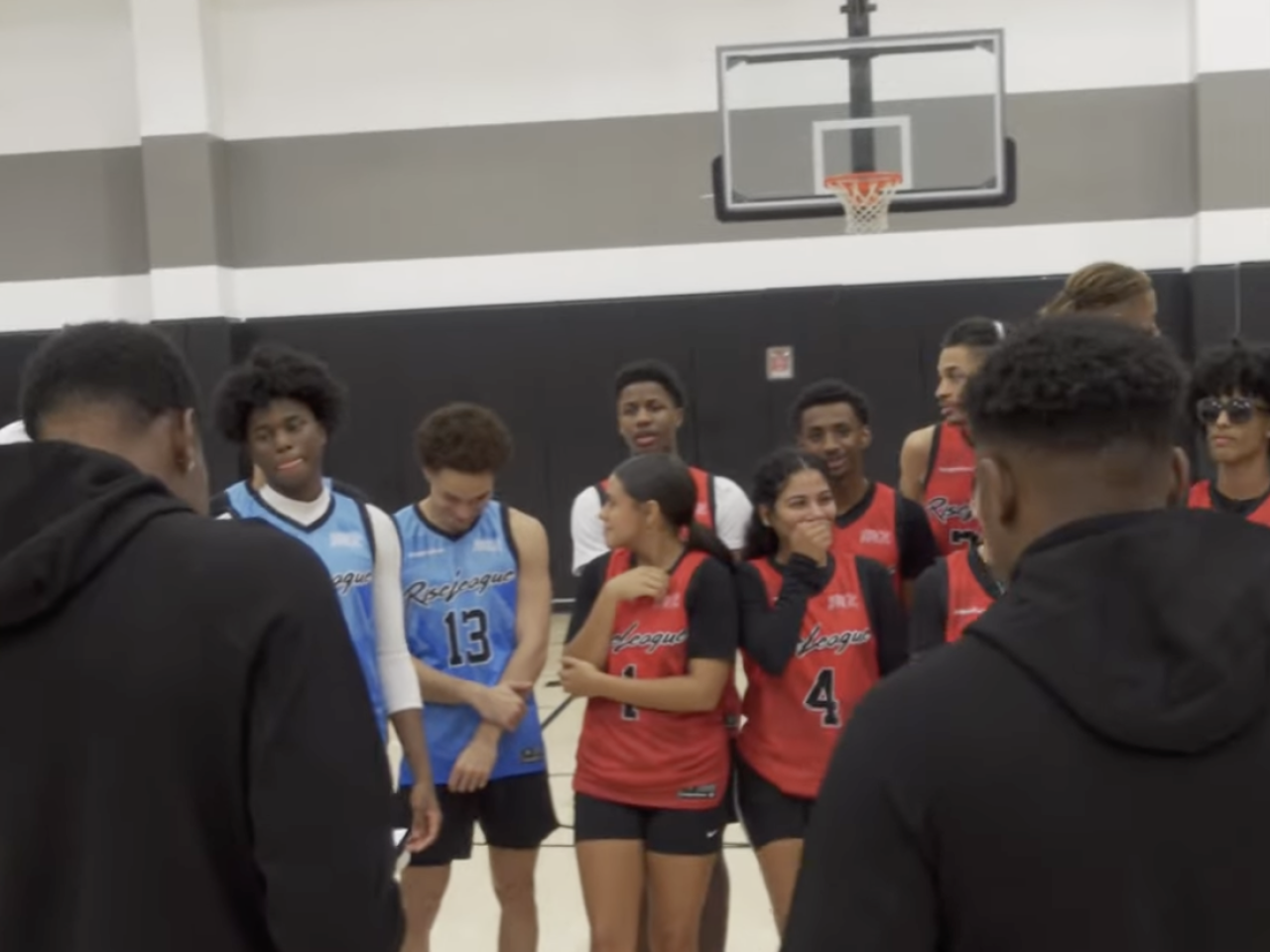 Two people reading a note to a basketball team 