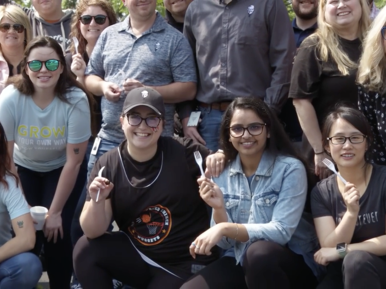 A group photo of people holding plastic forks