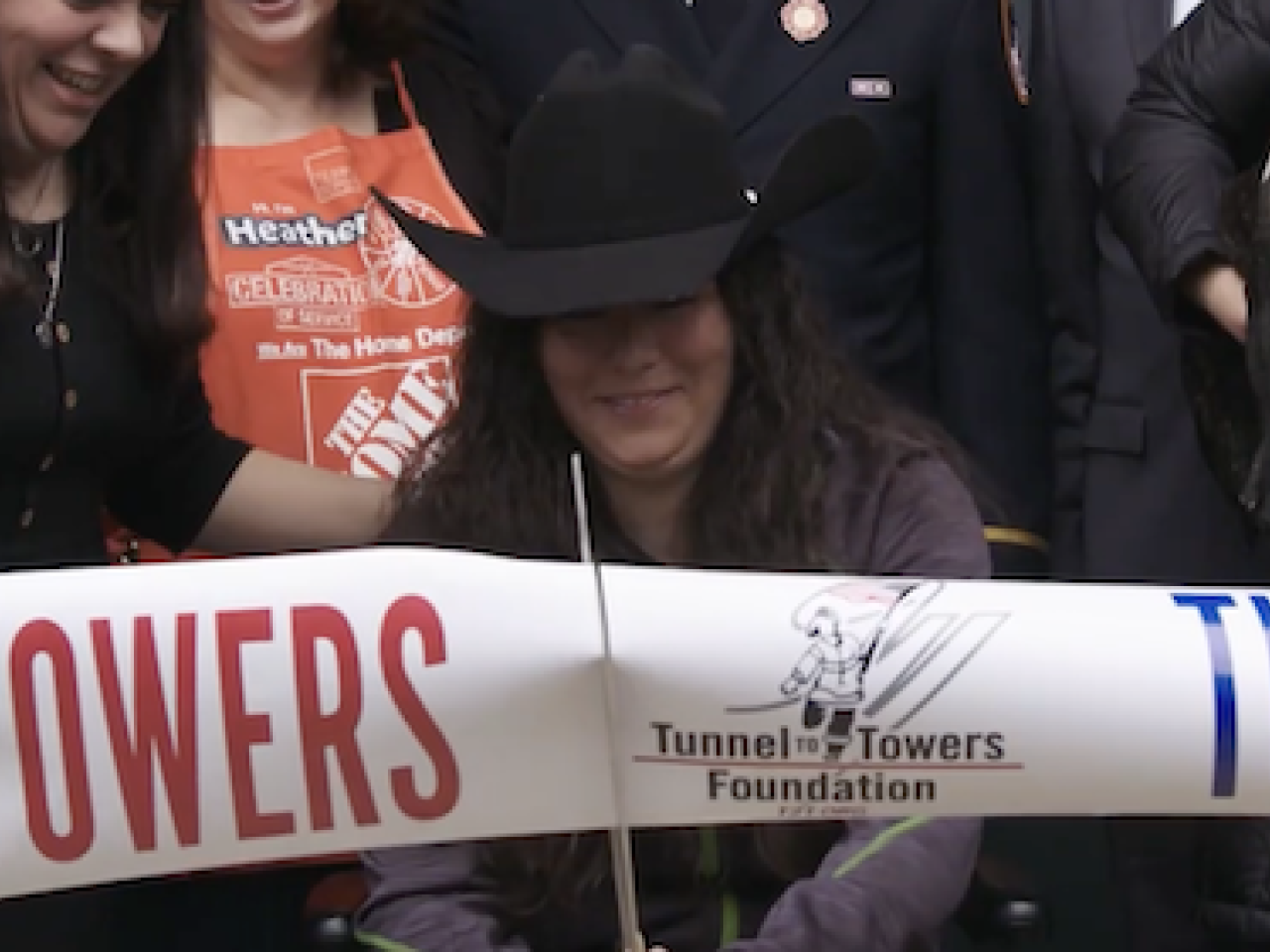 U.S. Army Specialist (SPC) Maggie Bilyeu shown cutting the ribbon in front of her new home.