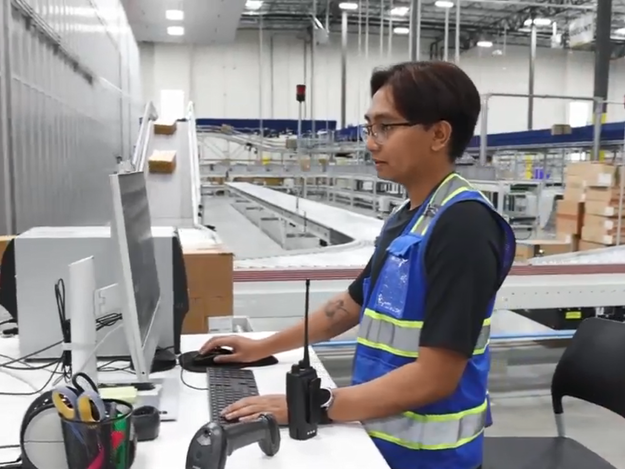 Jerenez Rivera standing at a computer station next to conveyor lines.