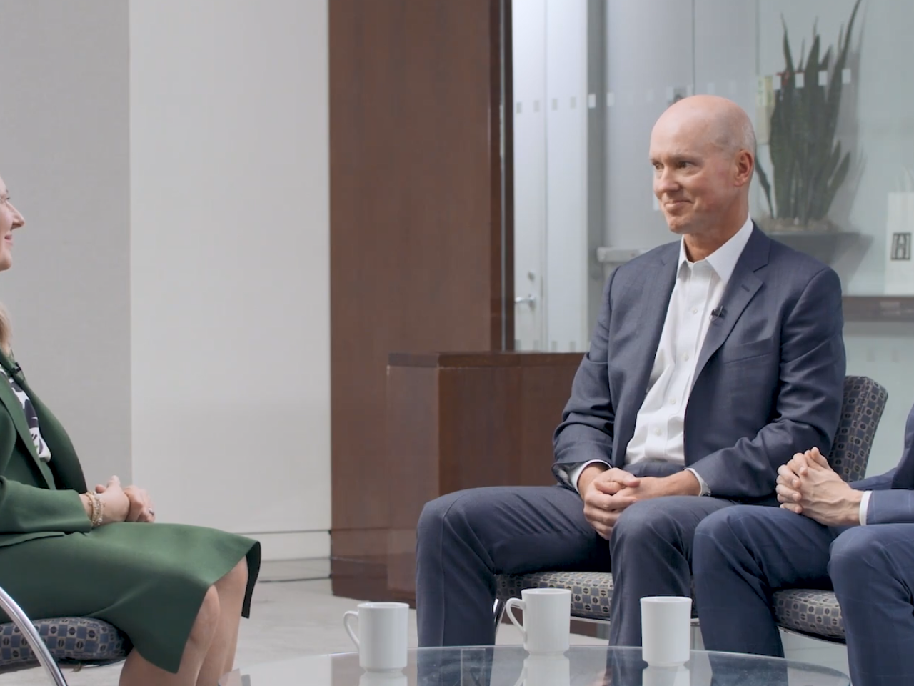 Three seated people talking.