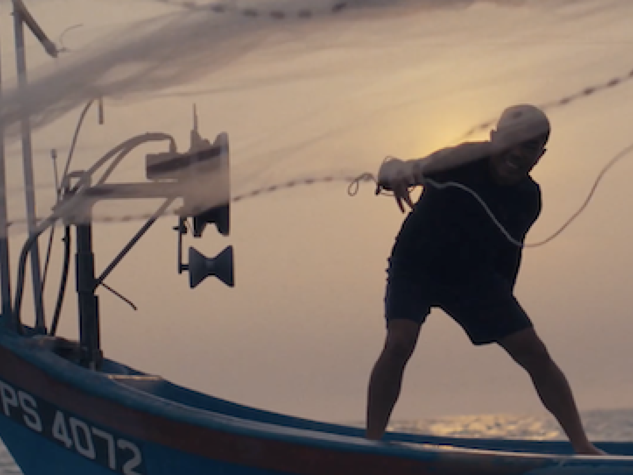 A fisherman casting a net from a fishing boat.