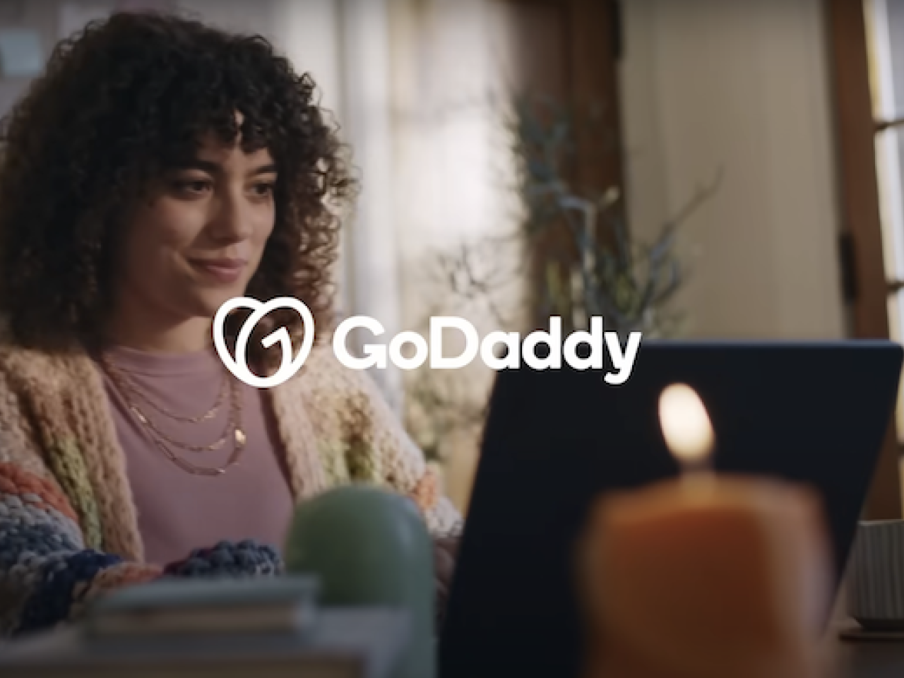 GoDaddy: Female seated in front of a laptop.