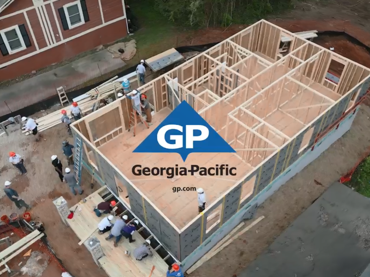 Aerial view of a home being built, many people at the site. Georgia-Pacific logo on top.