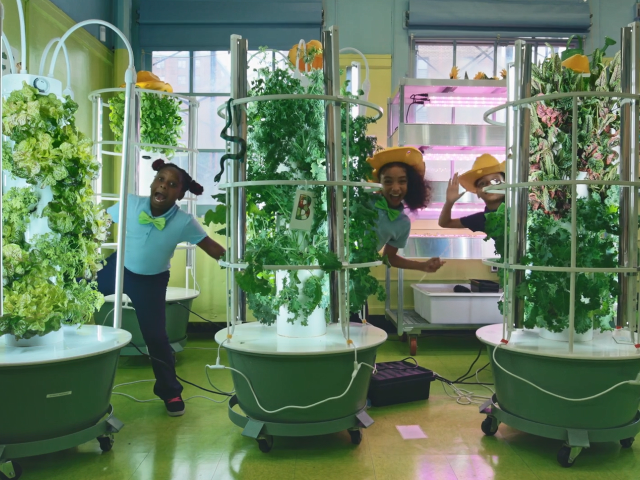 Children popping out from behind three tower gardens in a classroom.