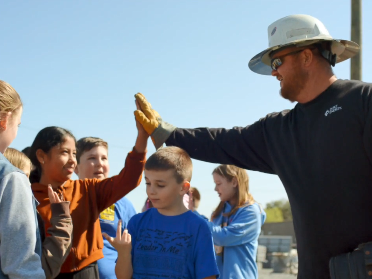 An employee in a hard hat gives a high five to a child.