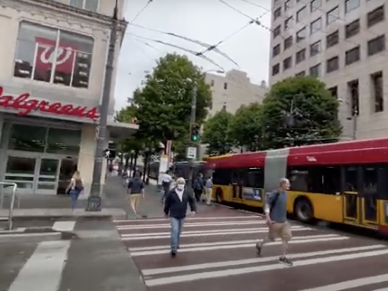 pedestrians crossing a city street in front of a Walgreens