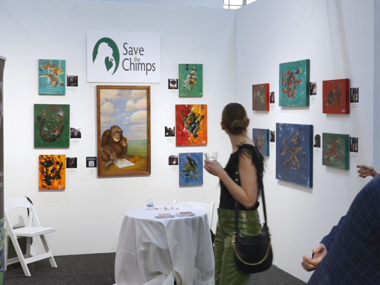 An art display "Save the Chimps" in a gallery. Patrons looking at the art.