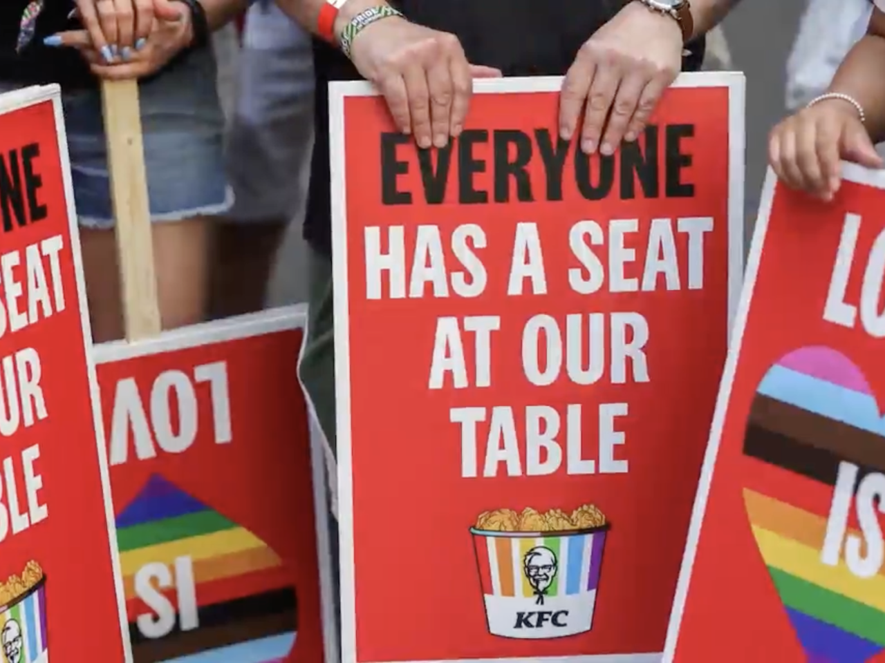 People holding signs that read "everyone has a seat at our table"