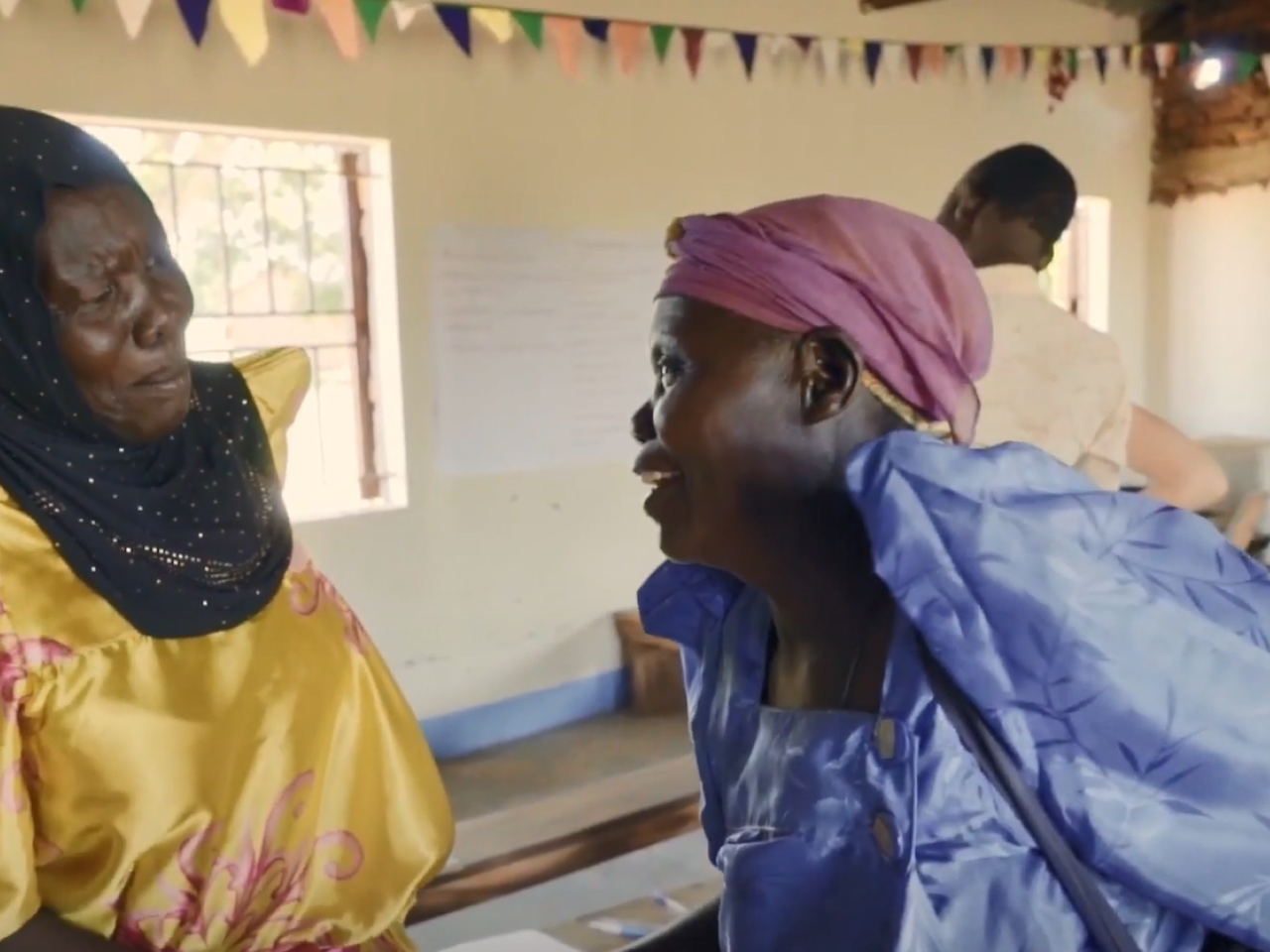 Two people smiling, talking to each other.